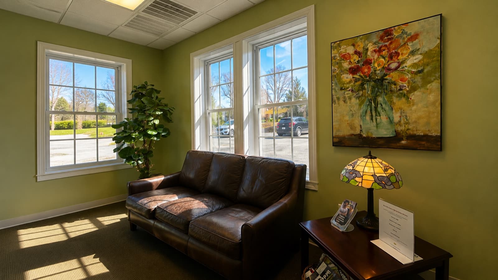 Waiting room with leather sofa, tall windows, and natural light